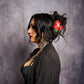 Woman with tattoos and a flower in her hair against a gray background